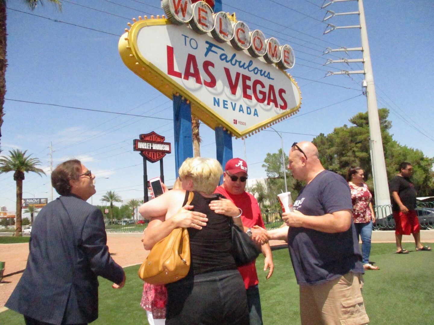 A group of people standing around in front of the welcome to fabulous las vegas sign.