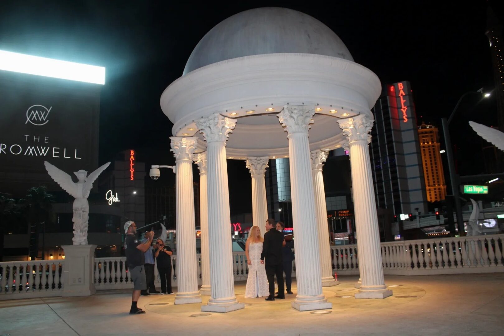 A couple is standing under a white gazebo.
