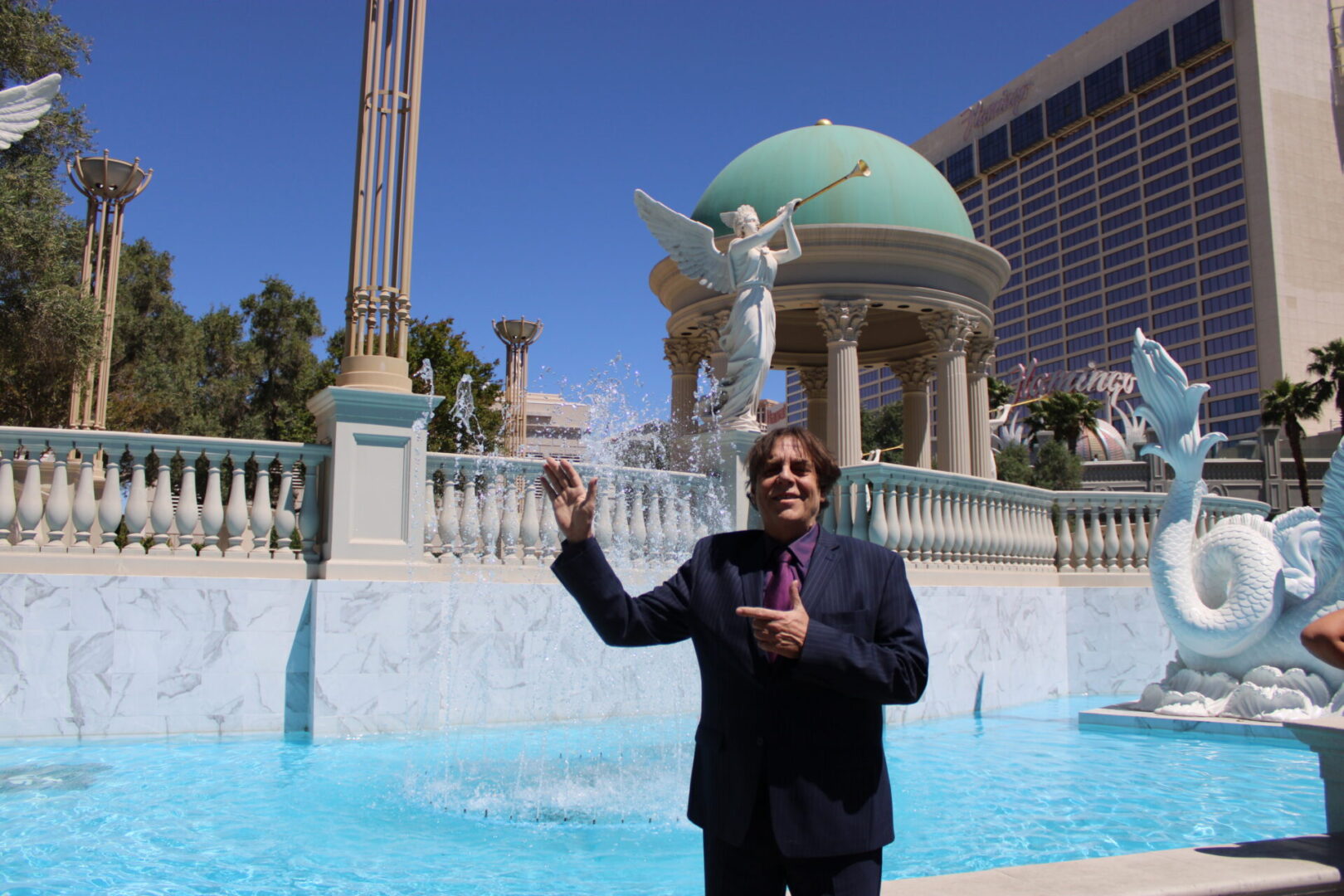A man in a suit and tie standing next to a pool.